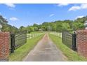 Long driveway with black wrought iron gate and white fence leads to home at 115 Ebenezer Church Rd, Fayetteville, GA 30215