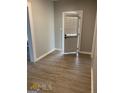 Neutral hallway with wood-look floors, leading to the exterior door with a window covering at 116 Stewart Ave, Jonesboro, GA 30236