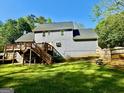 Back of the home featuring a wooden deck, lush green lawn, and mature trees at 149 Wimberly Way, Powder Springs, GA 30127