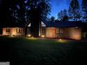 Exterior home view at night illuminated with landscape lighting and a stone and wood facade at 608 E Banks Rd, Fayetteville, GA 30214