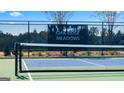 A close up of the pickleball court fence with an Oak Ridge Meadows banner and a partial view of the surrounding neighborhood at 591 Parnassus Rd, Locust Grove, GA 30248