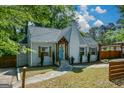 Quaint cottage with blue door, white brick chimney, mature shade trees, and a carport at 3164 Harris Dr, East Point, GA 30344