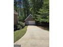 A detached brick garage with a concrete driveway is surrounded by lush greenery and mature trees at 45 Anna Dr, Covington, GA 30014