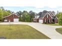 Spacious property featuring a brick house, detached garage, long driveway, and grassy lawn at 2351 Rabbit Farm Cir, Loganville, GA 30052