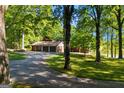Long, winding driveway leading to a home with a three-car garage surrounded by verdant trees and a tranquil lake at 4383 Pool Rd, Winston, GA 30187