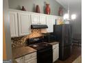 Cozy kitchen featuring modern appliances, granite countertops, white cabinets, and mosaic tile backsplash at 4379 Cross Ln, Decatur, GA 30035