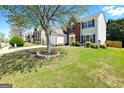 Lovely home with a lush green lawn and mature tree providing shade, two-car garage and brick accent at 340 Hammersmith Dr, Suwanee, GA 30024