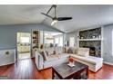 Open-concept living area with hardwood floors, stone fireplace, comfortable seating, and kitchen access at 2582 Rosecommons Dr, Hampton, GA 30228