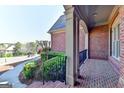 Covered front porch with brick flooring and view of landscaped front yard at 10125 Brixton Pl, Suwanee, GA 30024