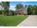 Expansive lawn highlights this stately two-story red brick home, complete with ample parking and lush trees at 419 Tea Rose N Ln, Stockbridge, GA 30281