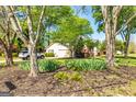Landscaped front yard with mature trees framing the house and driveway, providing a serene setting at 310 Hamdon Kells, Peachtree City, GA 30269