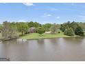 Aerial view of a brick home with a large pond, mature trees, and a green lawn at 39 Gabrielle Ct, Stockbridge, GA 30281