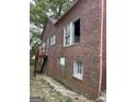 View of rear of red brick house in need of repair, including stairway to raised deck at 250 Mathewson Sw Pl, Atlanta, GA 30314
