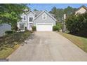 Charming two-story home featuring a gray exterior, white garage door, long driveway, and a unique purple front door at 750 Gates Ln, Alpharetta, GA 30022