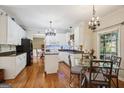 Bright eat-in kitchen features white cabinets, granite countertops, an island, and stylish chandeliers over a breakfast table at 750 Gates Ln, Alpharetta, GA 30022