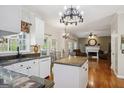 Open kitchen and living room concept with granite counters, white cabinets, hardwood floors, and stylish chandelier lighting at 750 Gates Ln, Alpharetta, GA 30022