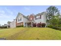 Two-story home with combination brick and siding facade, surrounded by green lawn and lush landscaping at 3156 Oak Ridge Ln, Loganville, GA 30052