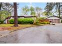 Landscaped front yard featuring mature trees and lush green bushes, providing privacy and curb appeal at 5082 Highland Hills Ct # 93, Stone Mountain, GA 30088