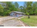 Ranch style home with gravel driveway and light blue siding and red shutters, surrounded by mature trees at 324 County Line Rd, Fayetteville, GA 30215