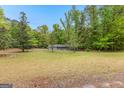 Ranch home with light blue siding and a well-manicured lawn, surrounded by lush, mature trees at 324 County Line Rd, Fayetteville, GA 30215