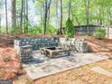 Outdoor fire pit area featuring stone accents and privacy from surrounding woods at 225 Suffolk Way, Mcdonough, GA 30252