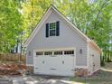 Two-car garage with stone-accented base, carriage doors, and green landscaping at 225 Suffolk Way, Mcdonough, GA 30252