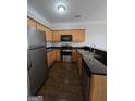 Well-lit kitchen with stainless steel appliances, dark countertops, and wood cabinets at 403 Buckboard Ln, Locust Grove, GA 30248