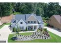 Stunning aerial view of the two-story home with manicured lawn, beautiful landscaping, and driveway at 5875 Windjammer Pt, Cumming, GA 30041