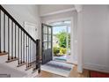 Bright and inviting foyer with hardwood floors, staircase, and a view of the landscaped front yard at 5875 Windjammer Pt, Cumming, GA 30041