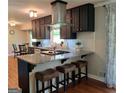 Modern kitchen featuring dark cabinets, granite countertops, breakfast bar, and stainless steel appliances at 1898 Mornington Ln, Snellville, GA 30078