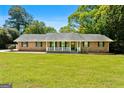 Traditional brick home with a front porch, complemented by a lush green lawn and mature trees at 25 Hickory Dr, Stockbridge, GA 30281
