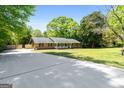 Classic brick home with a front porch and long driveway, set amidst a green lawn and mature trees at 25 Hickory Dr, Stockbridge, GA 30281