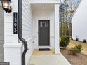 Close-up of a gray front door with a welcoming 'home' doormat, complemented by white brick and siding at 1393 Halpern Nw Ln, Kennesaw, GA 30144