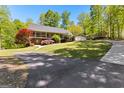 Charming ranch-style home with a detached garage and long, paved driveway surrounded by lush landscaping at 335 Winding Stream Trl, Hampton, GA 30228