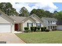Traditional single Gathering home showcasing a red front door and manicured landscaping at 12214 Cypress Way, Fayetteville, GA 30215