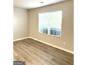 Bright bedroom featuring laminate flooring, window with blinds and neutral-colored walls at 1605 Hydrangea Ln, Mcdonough, GA 30253