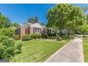Charming brick home featuring a well-maintained lawn, mature trees, and classic black shutters at 1325 E Forrest Ave, East Point, GA 30344