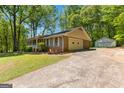 View of a single-story home with an attached two car garage and long driveway. Additional storage unit visible at 370 Merrydale Dr, Fayetteville, GA 30215