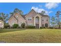 Brick home boasts an arched entryway, a manicured front lawn, and timeless architectural details, perfect for families at 3705 Royer Ln, Hampton, GA 30228