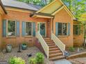 Inviting brick home entrance featuring a classic doorway, painted shutters, and beautiful landscaping at 318 Dogwood Trce, Mcdonough, GA 30252