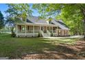 Traditional-style single-Gathering home showcases a spacious front yard with mature trees and a long front porch at 423 Bear Creek Trl, Hampton, GA 30228