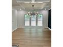 Bright living room with hardwood floors, modern chandelier, white trim, and large windows for an open, airy feel at 409 Saint Surrey Way, Ellenwood, GA 30294