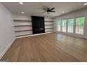 Spacious living room with hardwood floors, a sleek fireplace, floating shelves, and natural light from large windows at 409 Saint Surrey Way, Ellenwood, GA 30294