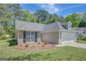 Well-manicured lawn surrounds a lovely home with stone and siding accents, complemented by a spacious two-car garage at 8032 Highland Pkwy, Fairburn, GA 30213