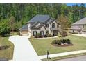 Aerial view of brick home with a three-car garage, manicured lawn, and verdant treeline at 266 Shellbark Dr, Mcdonough, GA 30252