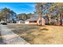 One-story brick home with attached garage surrounded by large front yard and mature trees at 113 Elmwood Dr, Hampton, GA 30228