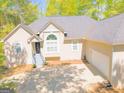 Traditional home showing garage and front entrance with landscaped yard and mature trees at 1252 Heritage Dr, Villa Rica, GA 30180