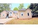Beige home featuring an attached garage, a manicured lawn, and plenty of trees at 1252 Heritage Dr, Villa Rica, GA 30180