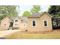 Beige stucco home featuring an attached garage, a well maintained lawn, and mature trees at 1252 Heritage Dr, Villa Rica, GA 30180