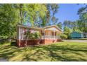 Inviting single-story home featuring a cozy front porch, complemented by a green lawn and mature trees in the background at 842 Brighton Dr, Lawrenceville, GA 30043